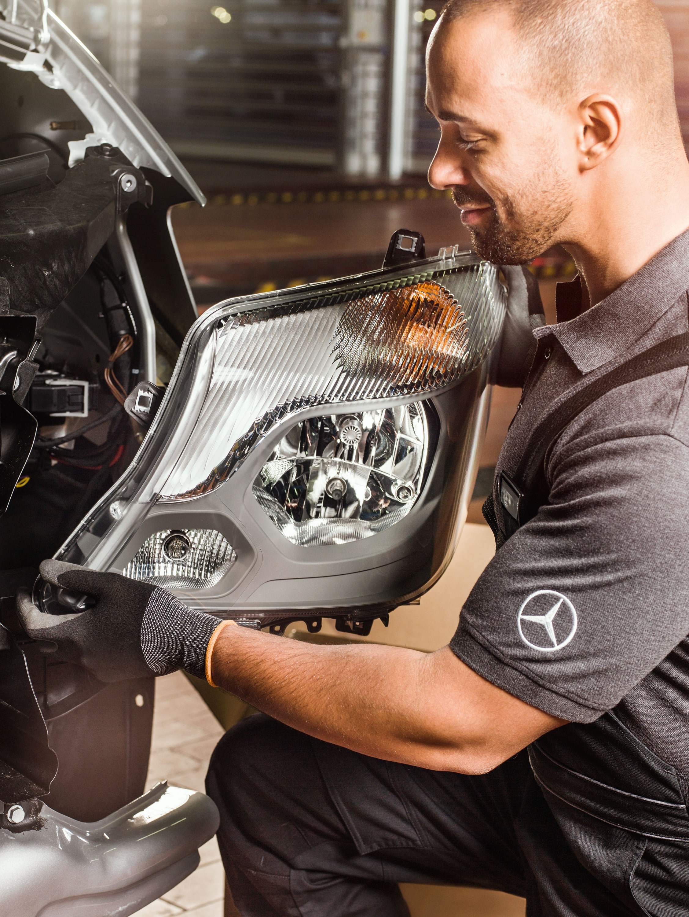 Monteur controleert Mercedes-Benz Originele Onderdelen voor een open Sprinter-motor volgens de onderdelencatalogus.