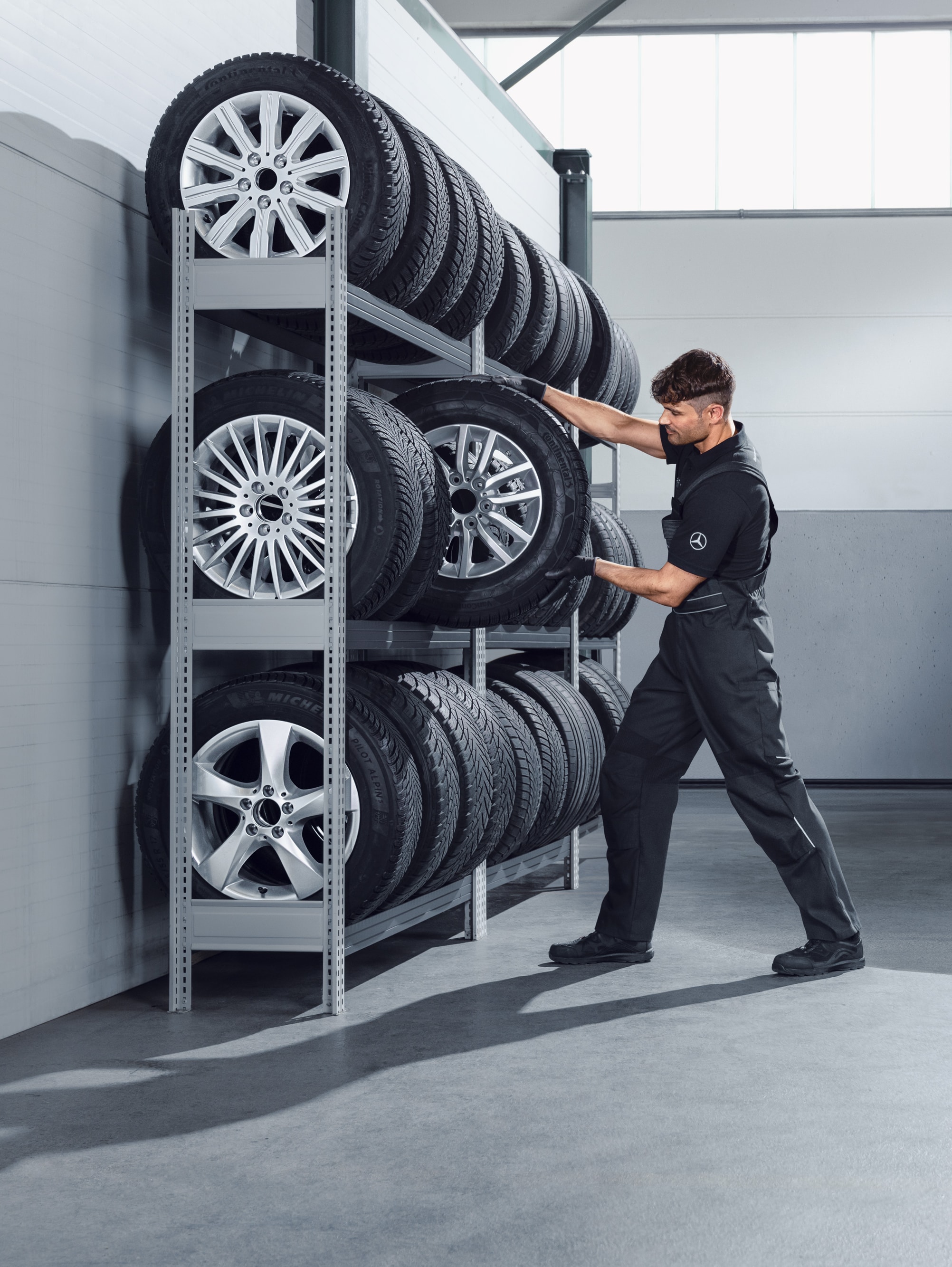 Monteur kiest Mercedes-Benz complete winterwielen voor een witte Sprinter uit de werkplaatsplank.