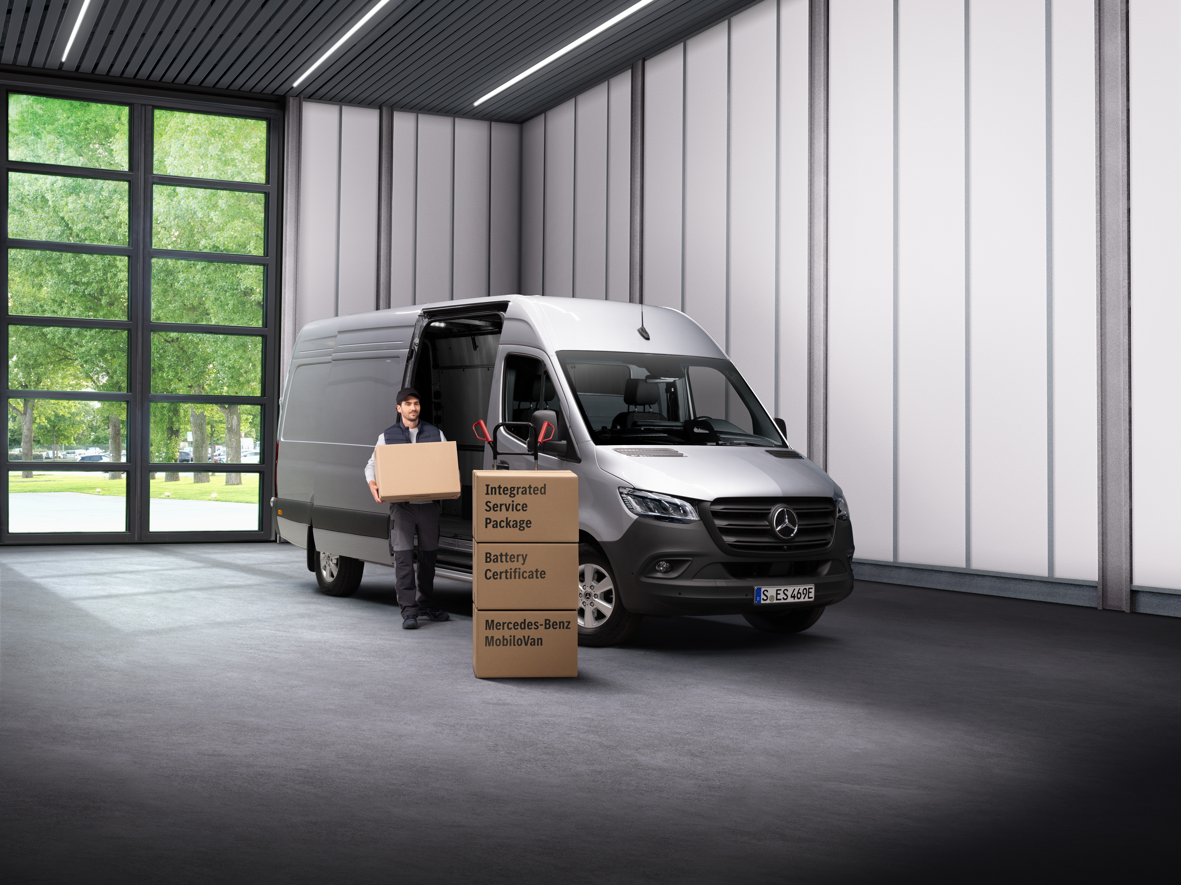 Mercedes-Benz - Service pour véhicules électriques Un employé du service électrique de Mercedes-Benz transportant des boîtes hors d’une agence de transport