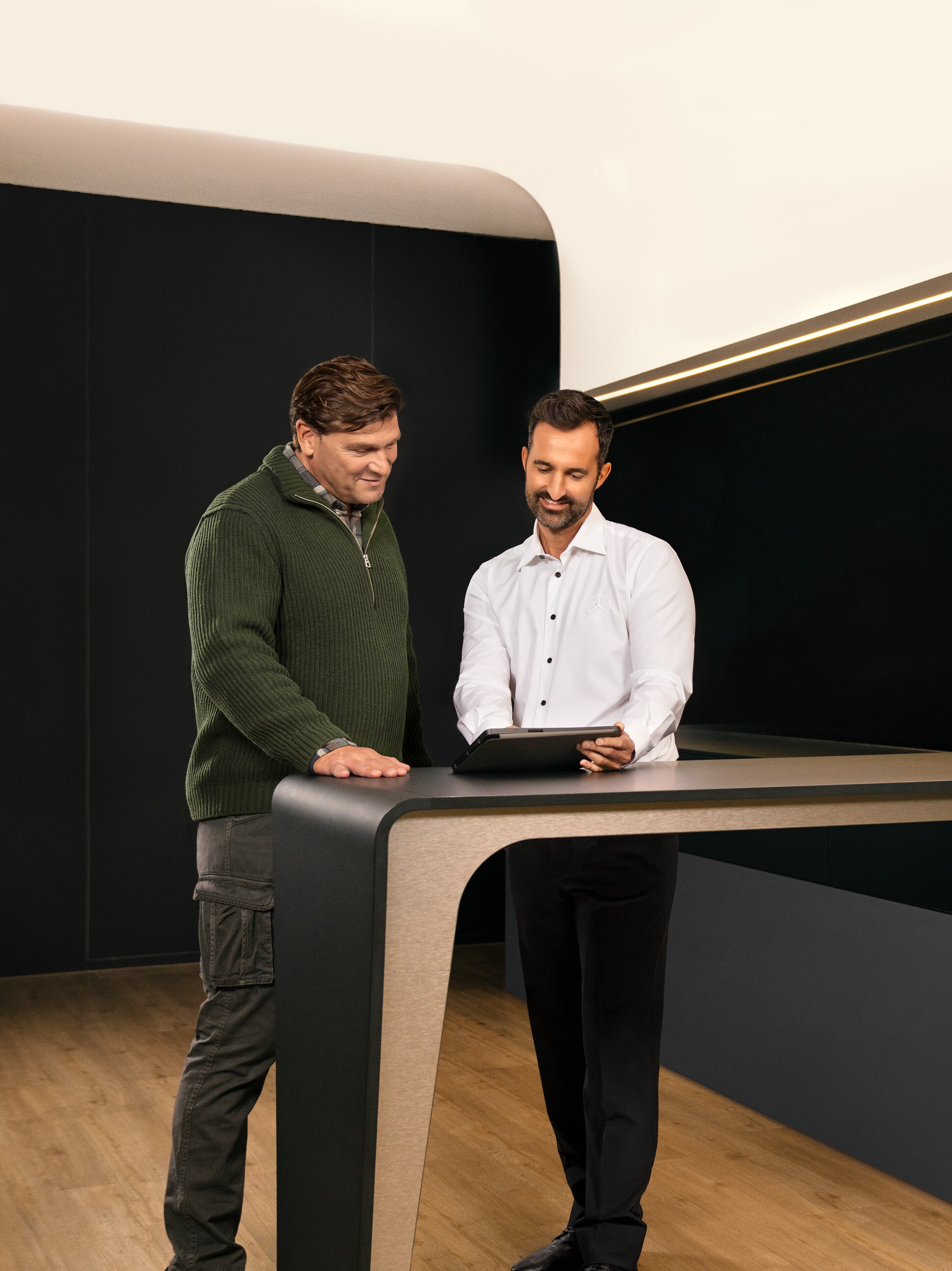 Twee mannen bespreken Mercedes-Benz ServiceCare pakketten voor bedrijfswagens via een tablet.