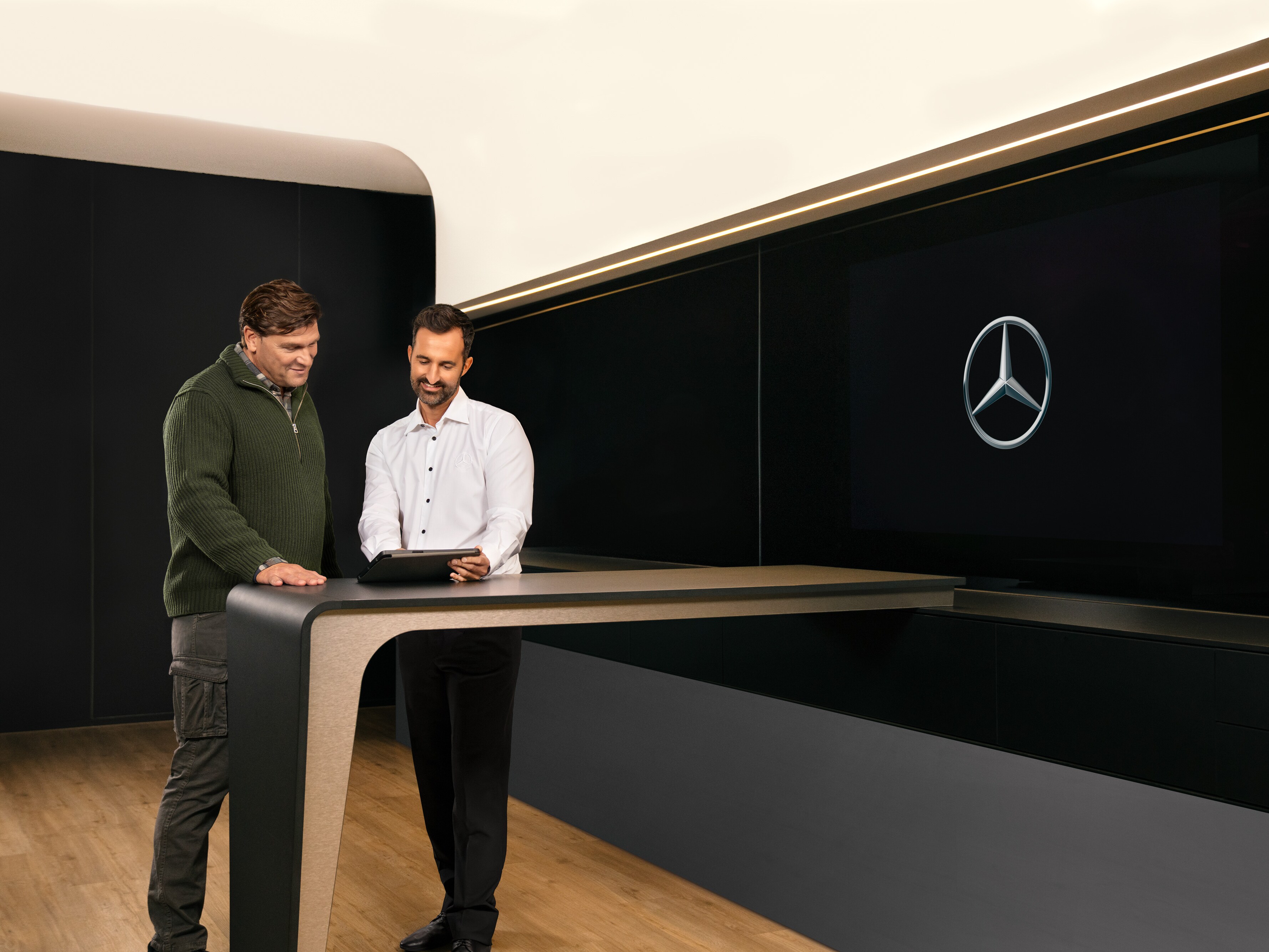 Twee mannen bespreken Mercedes-Benz ServiceCare pakketten voor bedrijfswagens via een tablet.