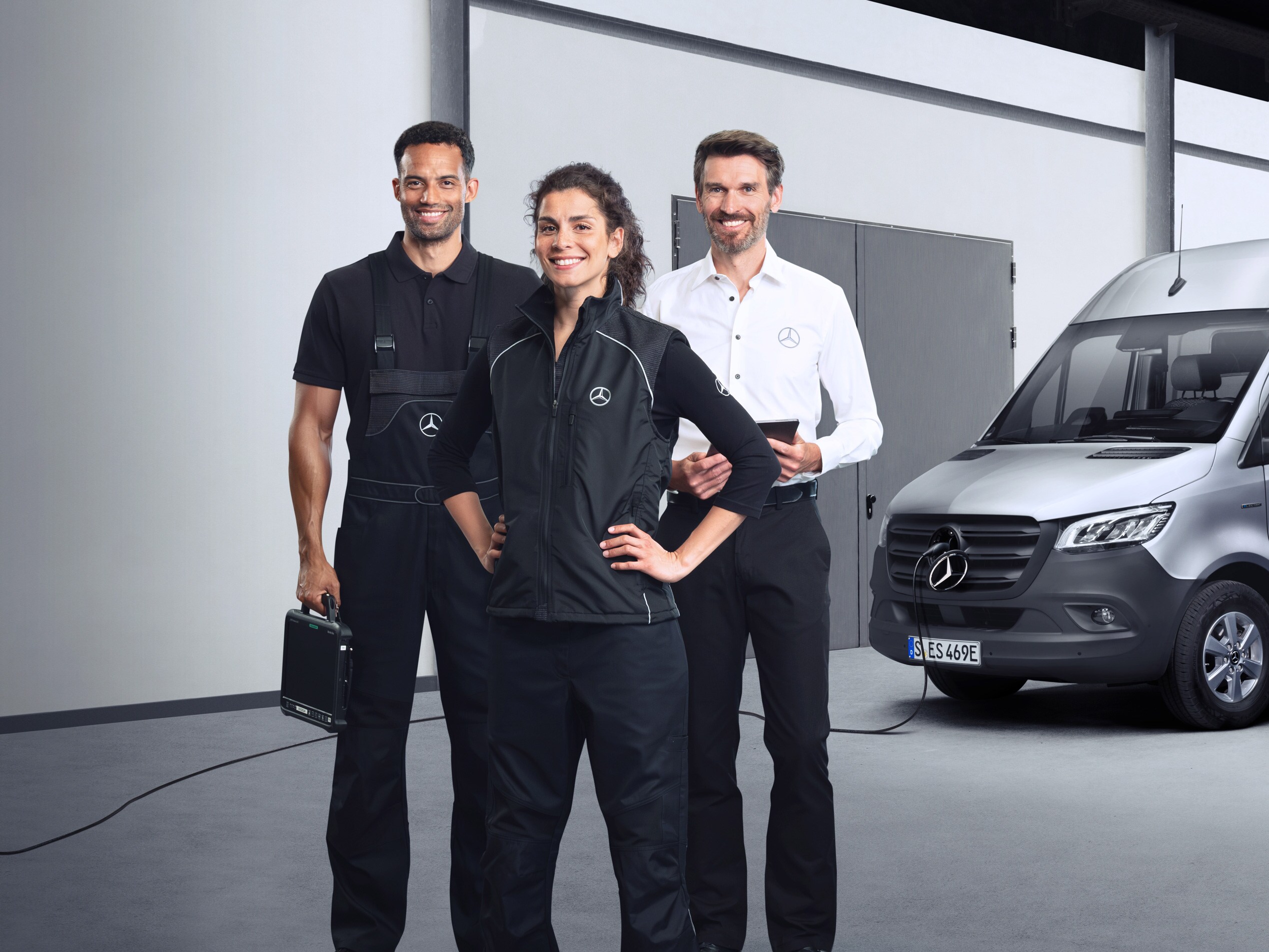 Drie medewerkers staan voor een zilveren Mercedes-Benz eSprinter met aangesloten laadkabel als symbool voor service elektrische bedrijfswagens.
