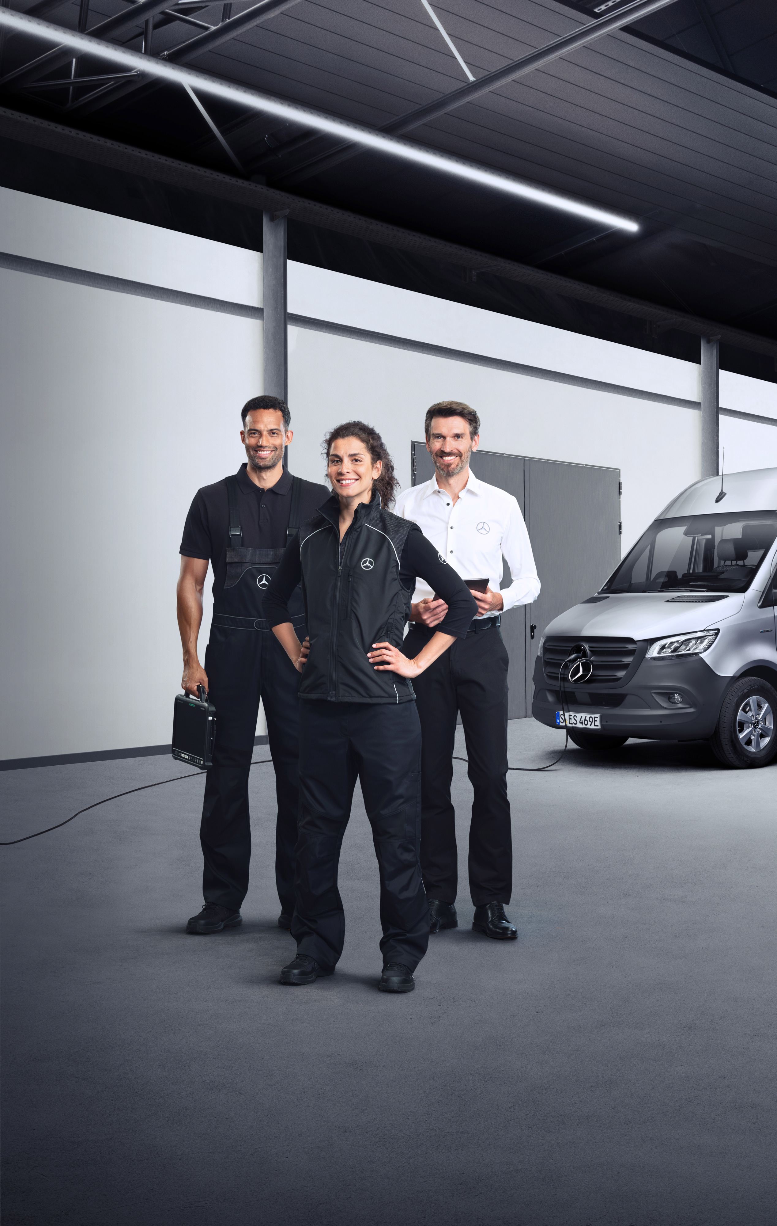 Mercedes-Benz | Servicesoverzicht | Services elektrische bedrijfswagens Drie medewerkers die voor een zilveren Mercedes-Benz eSprinter staan met aangesloten laadkabel.