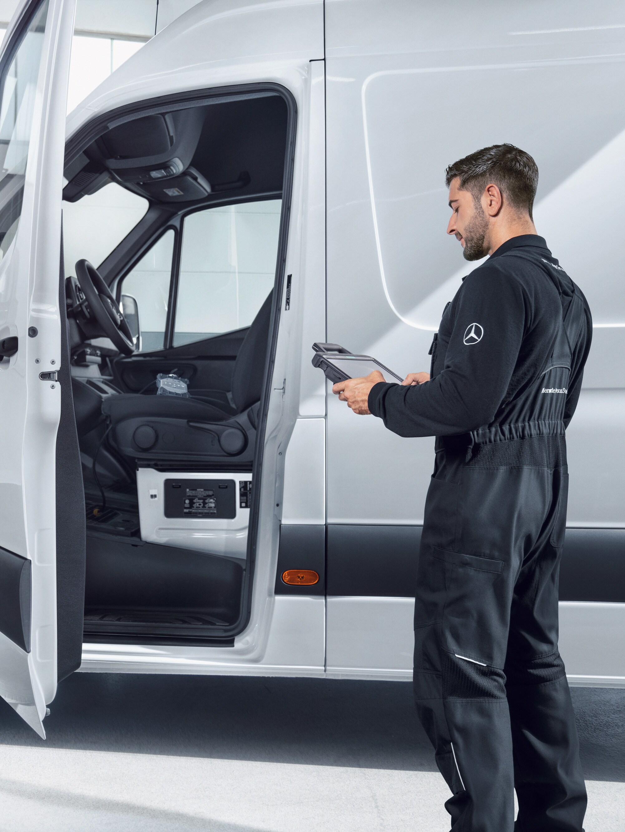 Een medewerker die een Mercedes-Benz bedrijfswagen inspecteert en betrouwbare servicekwaliteit biedt voor onderhoud en reparaties.