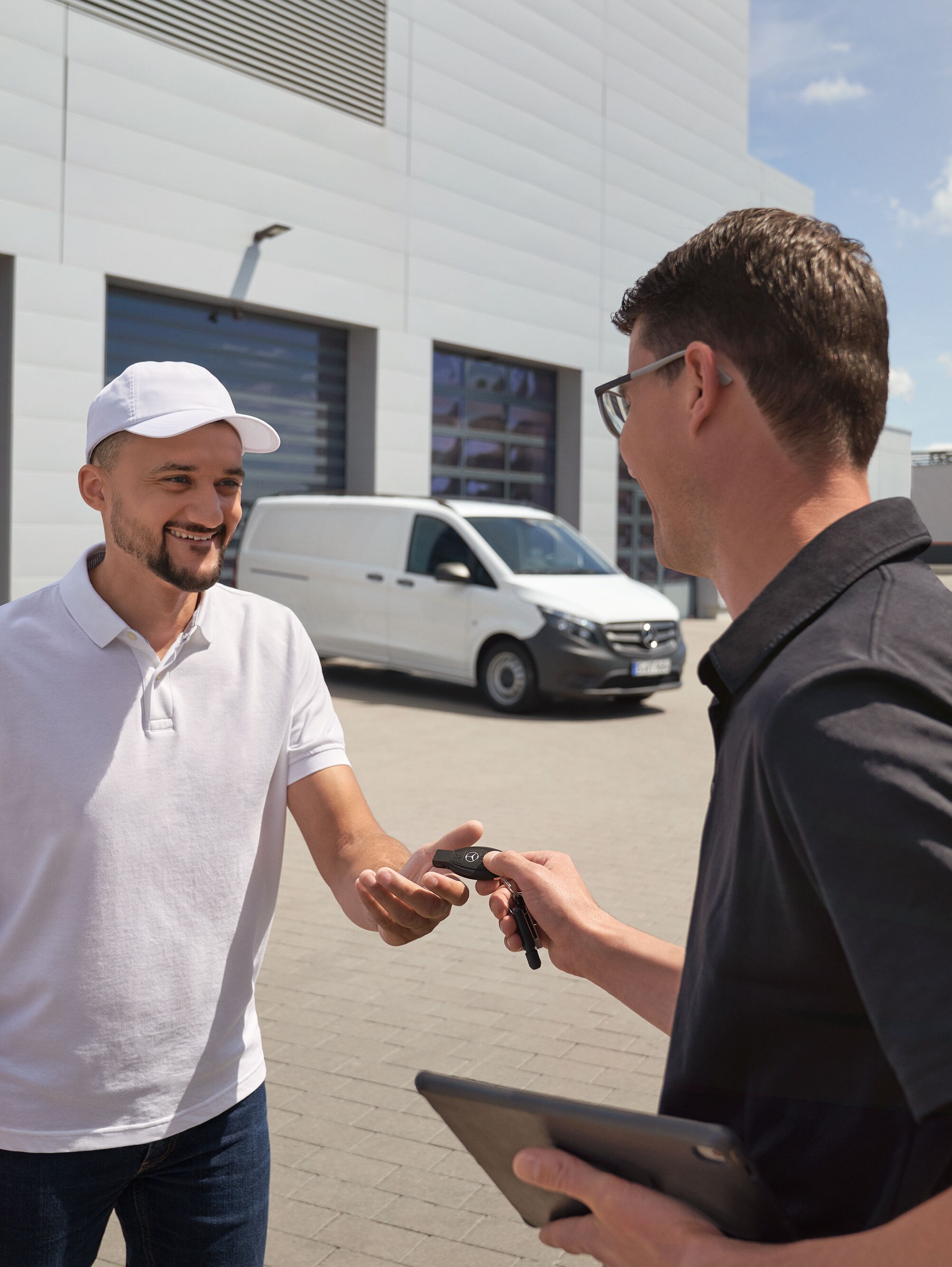 Représentant SAV Mercedes-Benz remettant les clés à un client, avec un utilitaire léger Mercedes-Benz Vito blanc à l'arrière-plan.