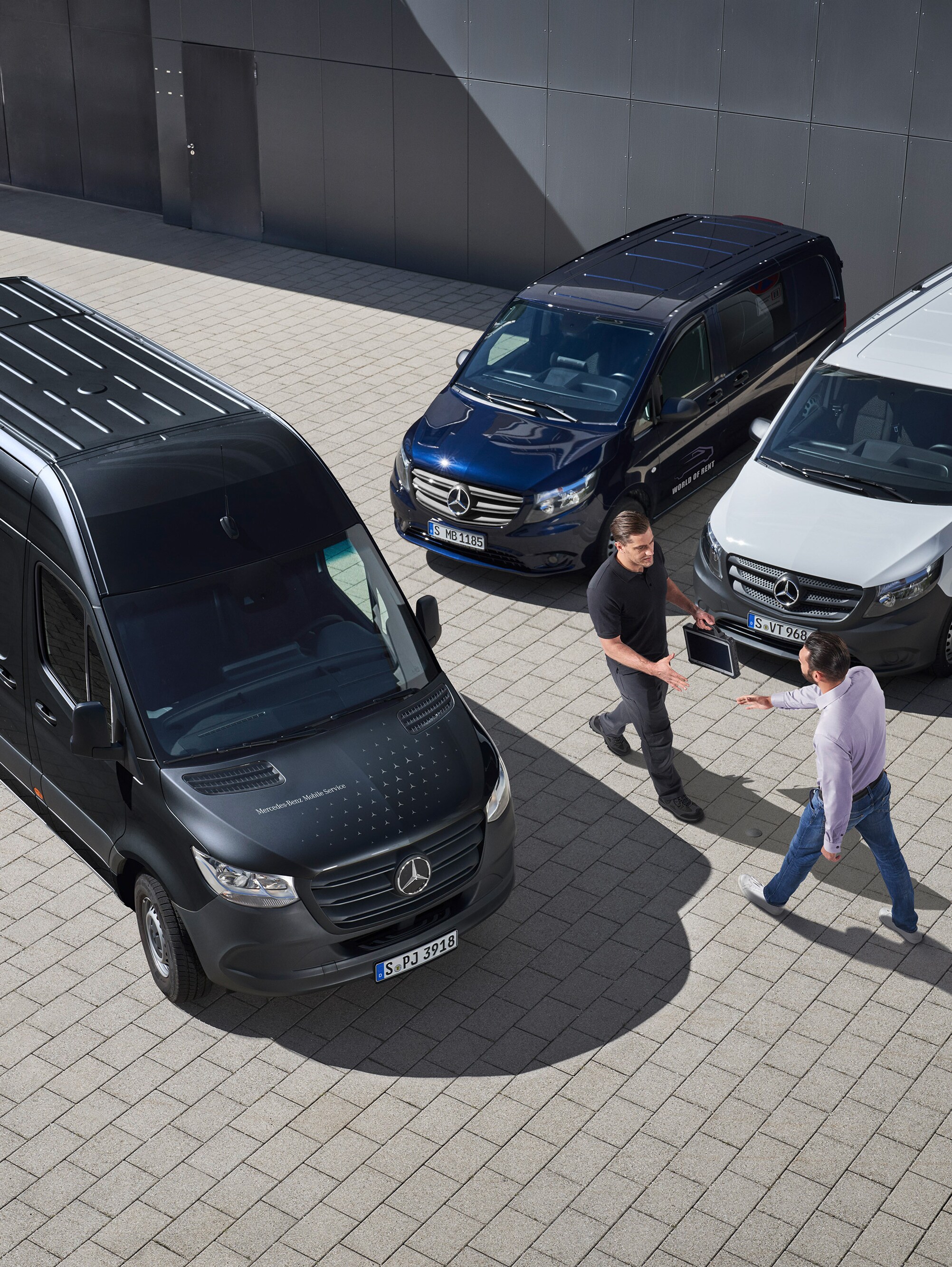 Twee mannen begroeten elkaar tussen Mercedes-Benz Bedrijfswagens als symbool voor mobiele service.