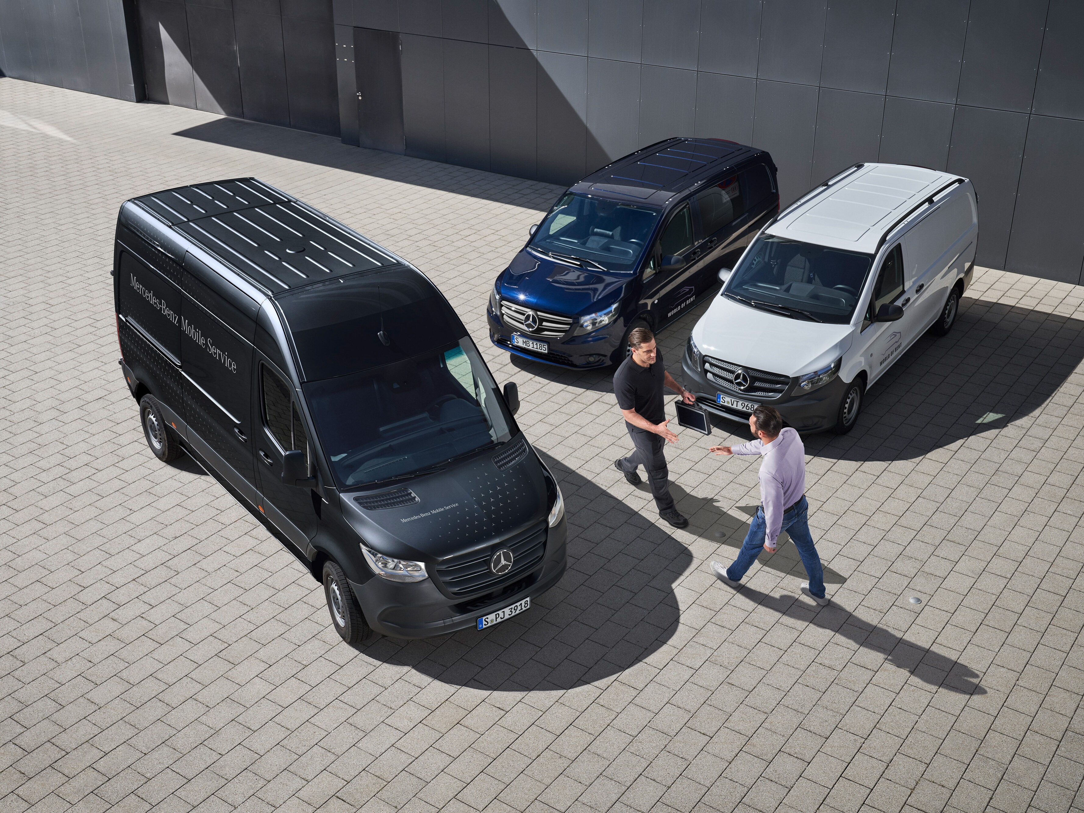 Twee mannen begroeten elkaar tussen Mercedes-Benz Bedrijfswagens als symbool voor mobiele service.