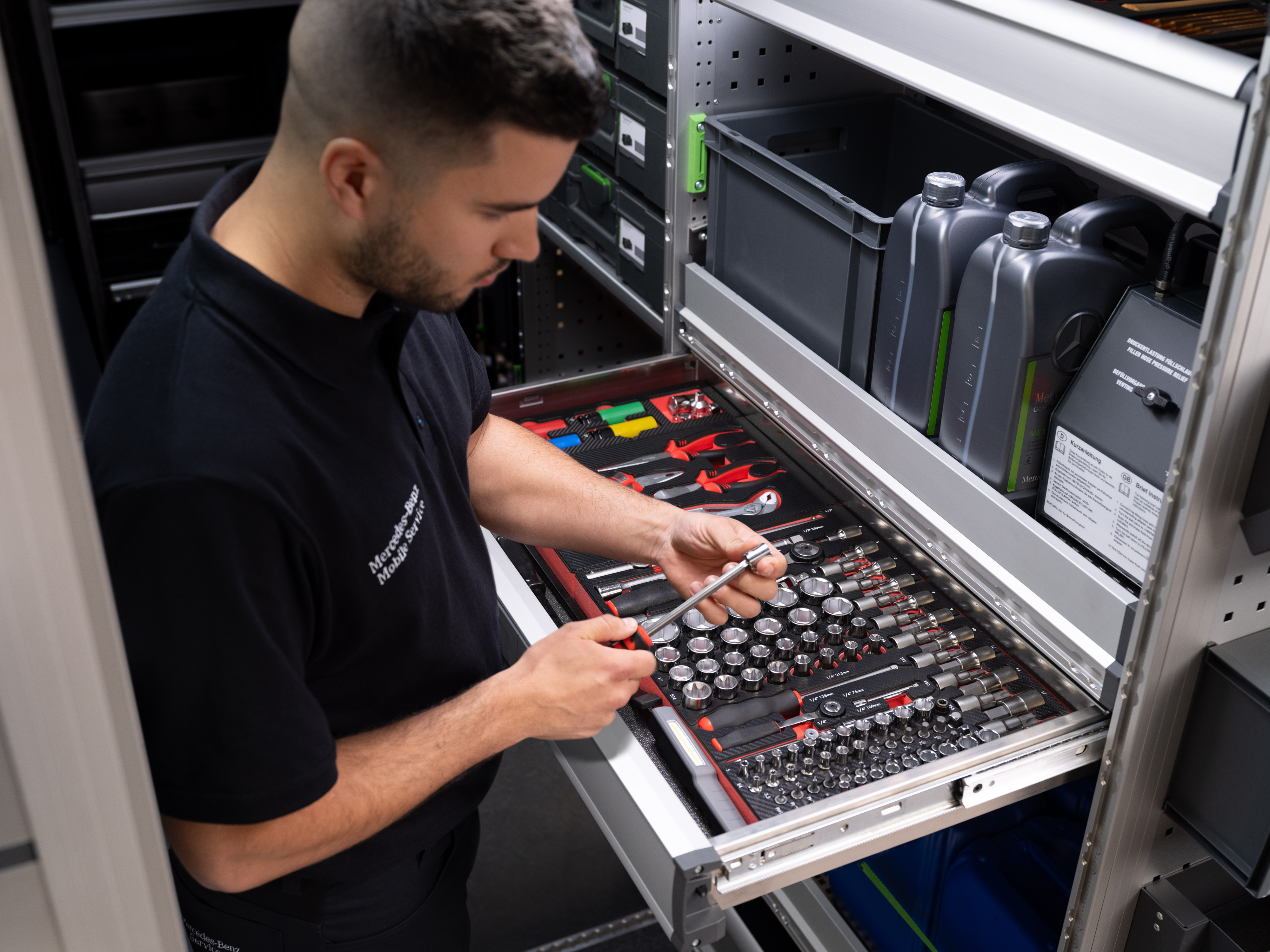 Mercedes-Benz | Service mobile | Électronique Un technicien sélectionne un article dans un tiroir rempli d'outils.