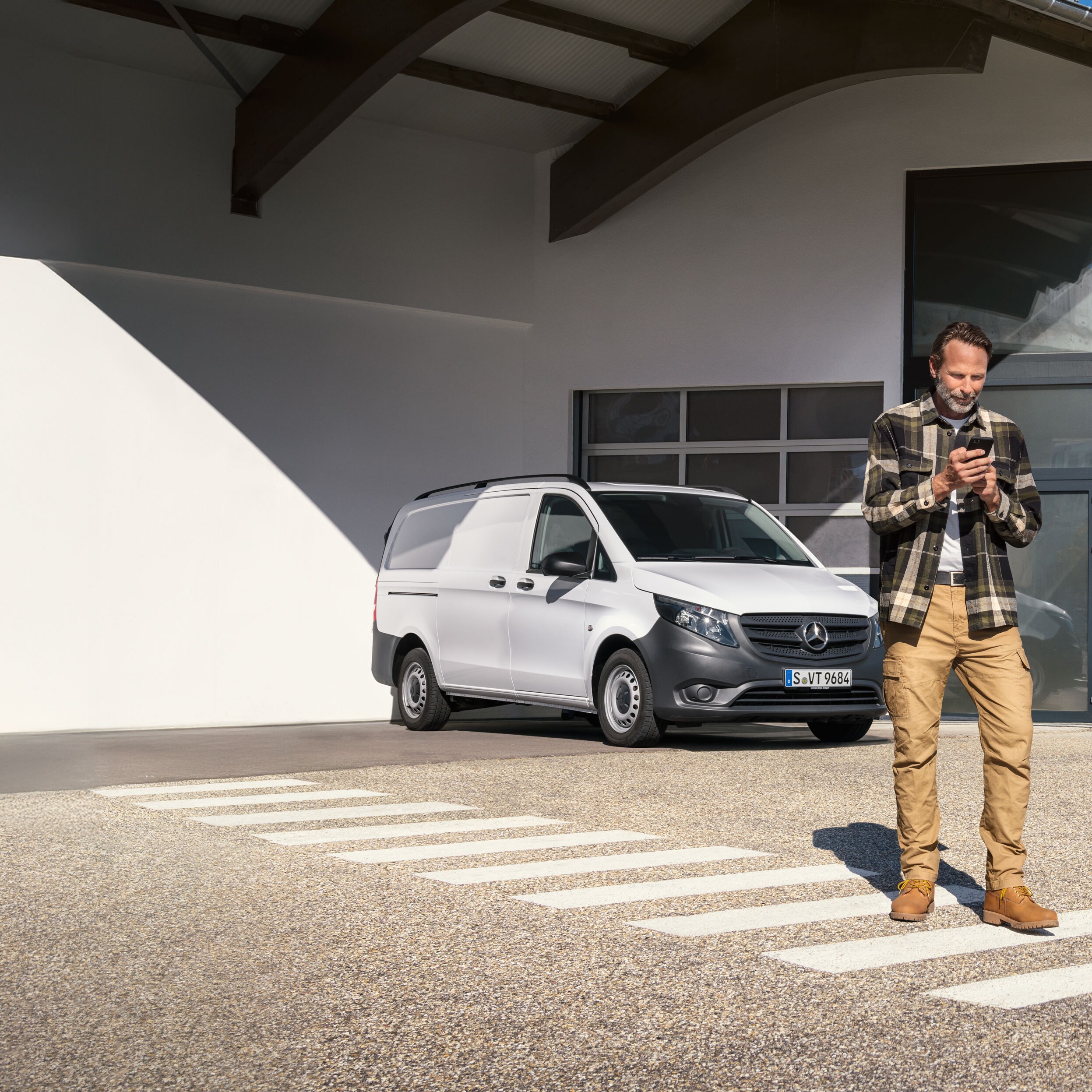 Le client prend rendez-vous depuis son téléphone portable alors qu'il se trouve devant un utilitaire léger Mercedes-Benz Vito.