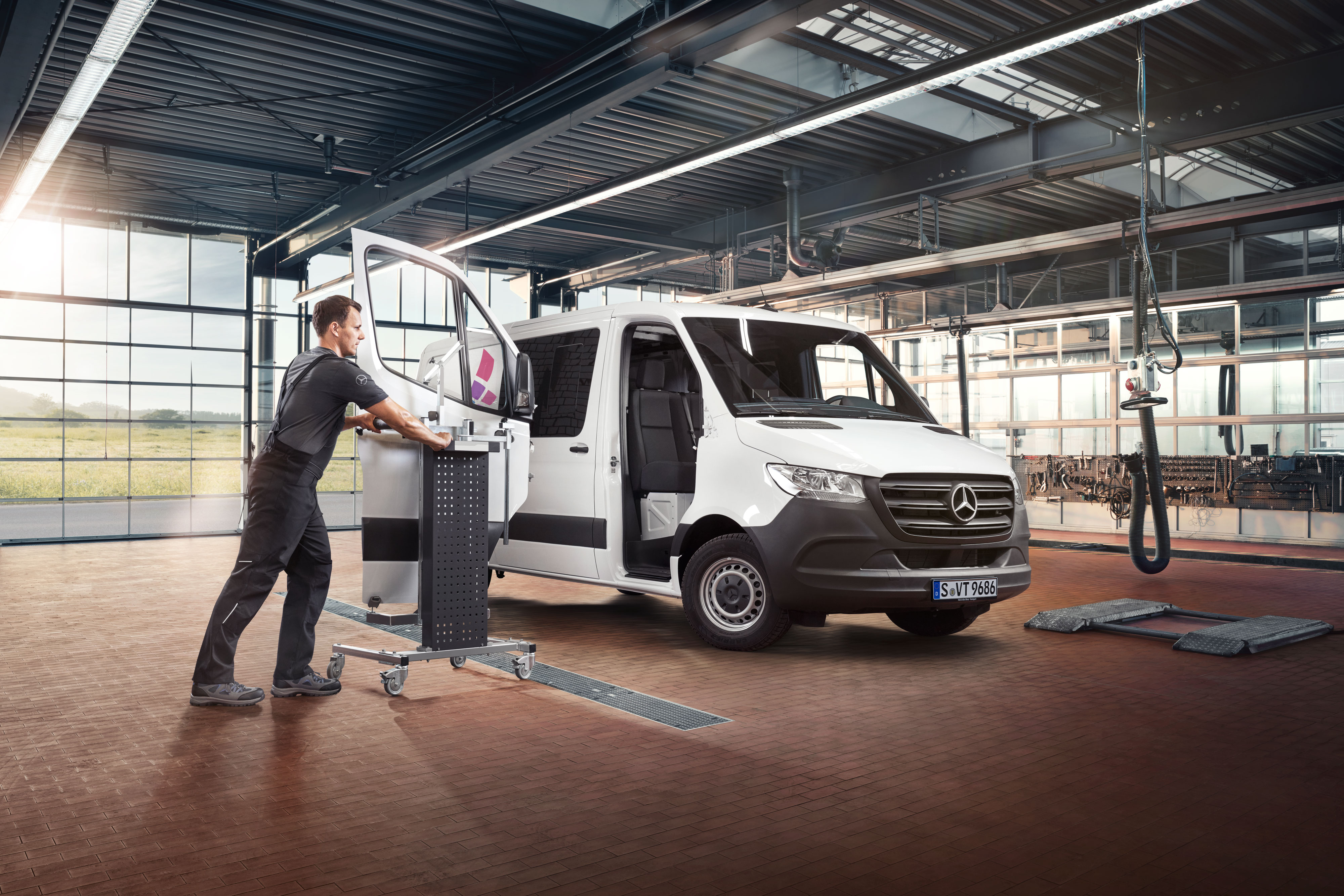 Mercedes-Benz | Réparation Un mécanicien fixe la porte d’une Mercedes-Benz Sprinter blanche.