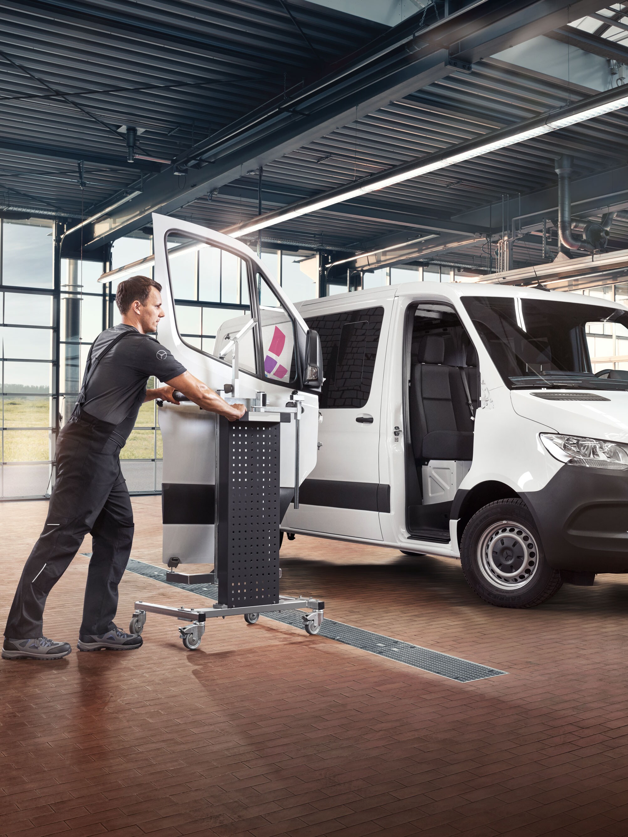 Monteur monteert de deur van een witte Mercedes-benz Sprinter.