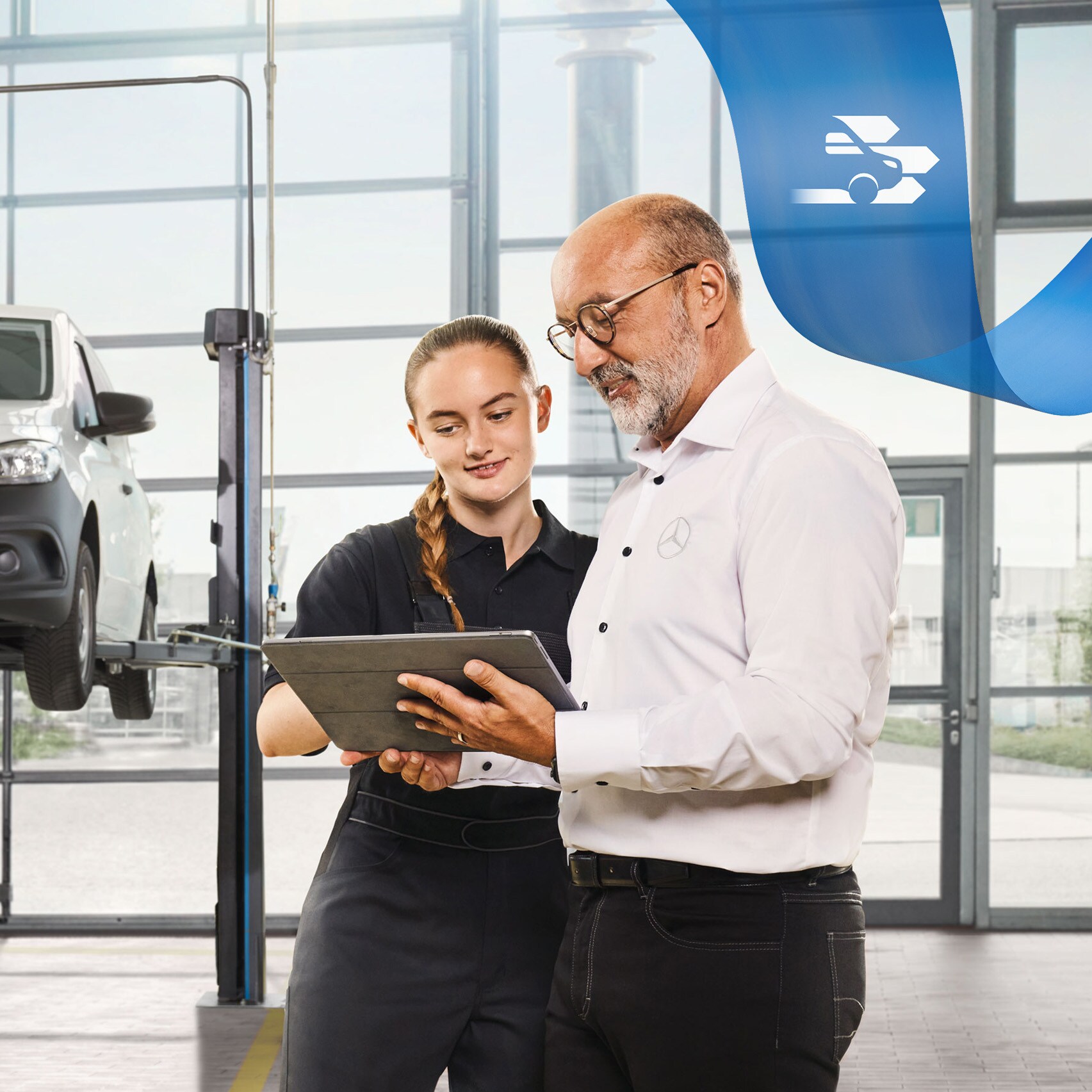 Twee medewerkers bespreken de bedrijfswagenservice bij een opgekrikte Mercedes-Benz bedrijfswagen in de werkplaats.