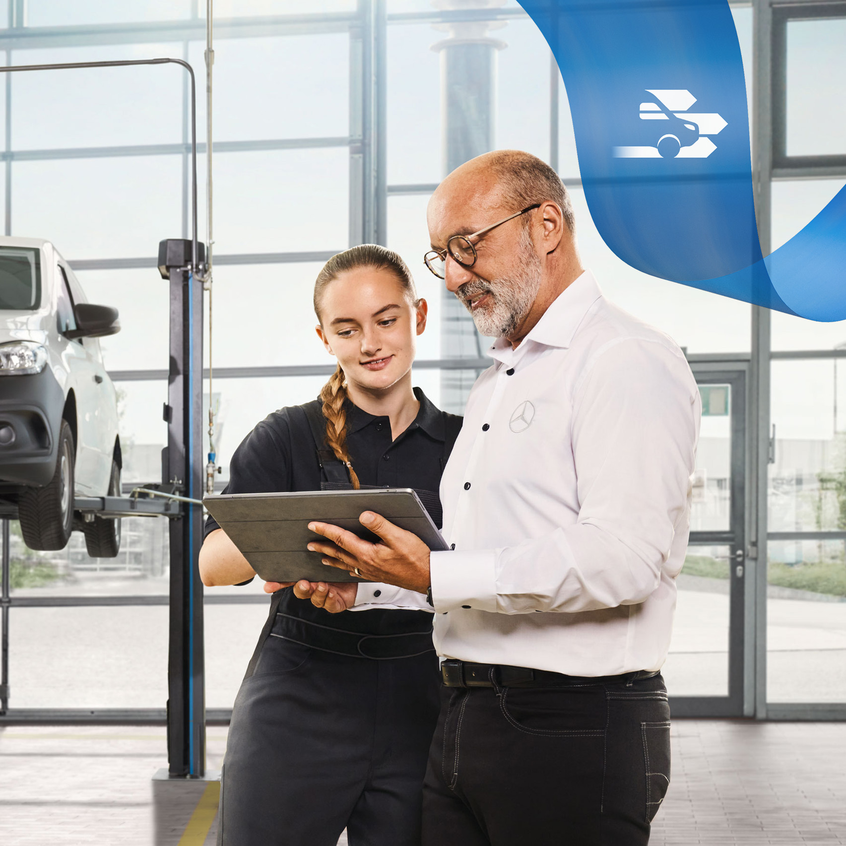 Mercedes-Benz Onderhoud Twee medewerkers bespreken de bedrijfswagenservice bij een opgekrikte Mercedes-Benz bedrijfswagen in de werkplaats.
