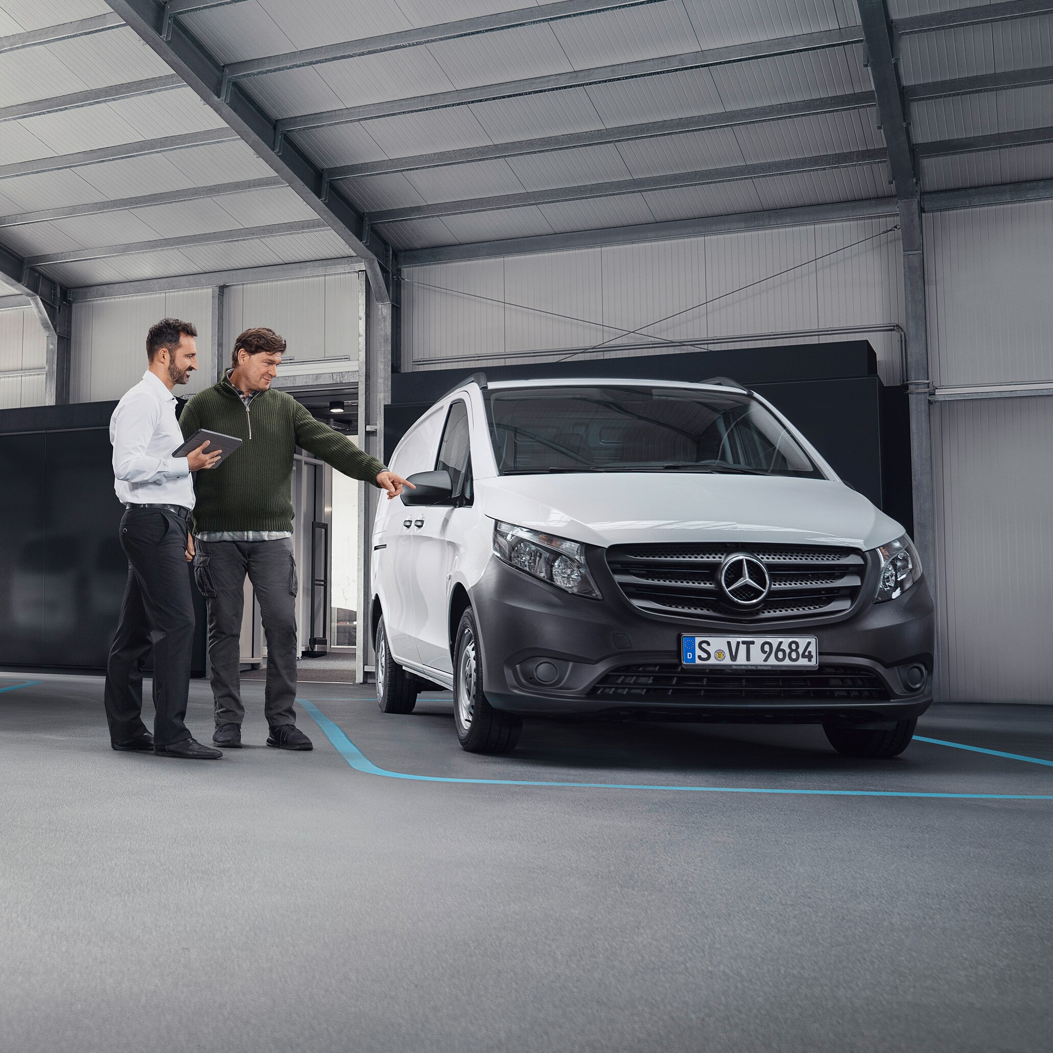 Agent SAV de Mercedes-Benz avec un client chez un partenaire de service devant un utilitaire léger.