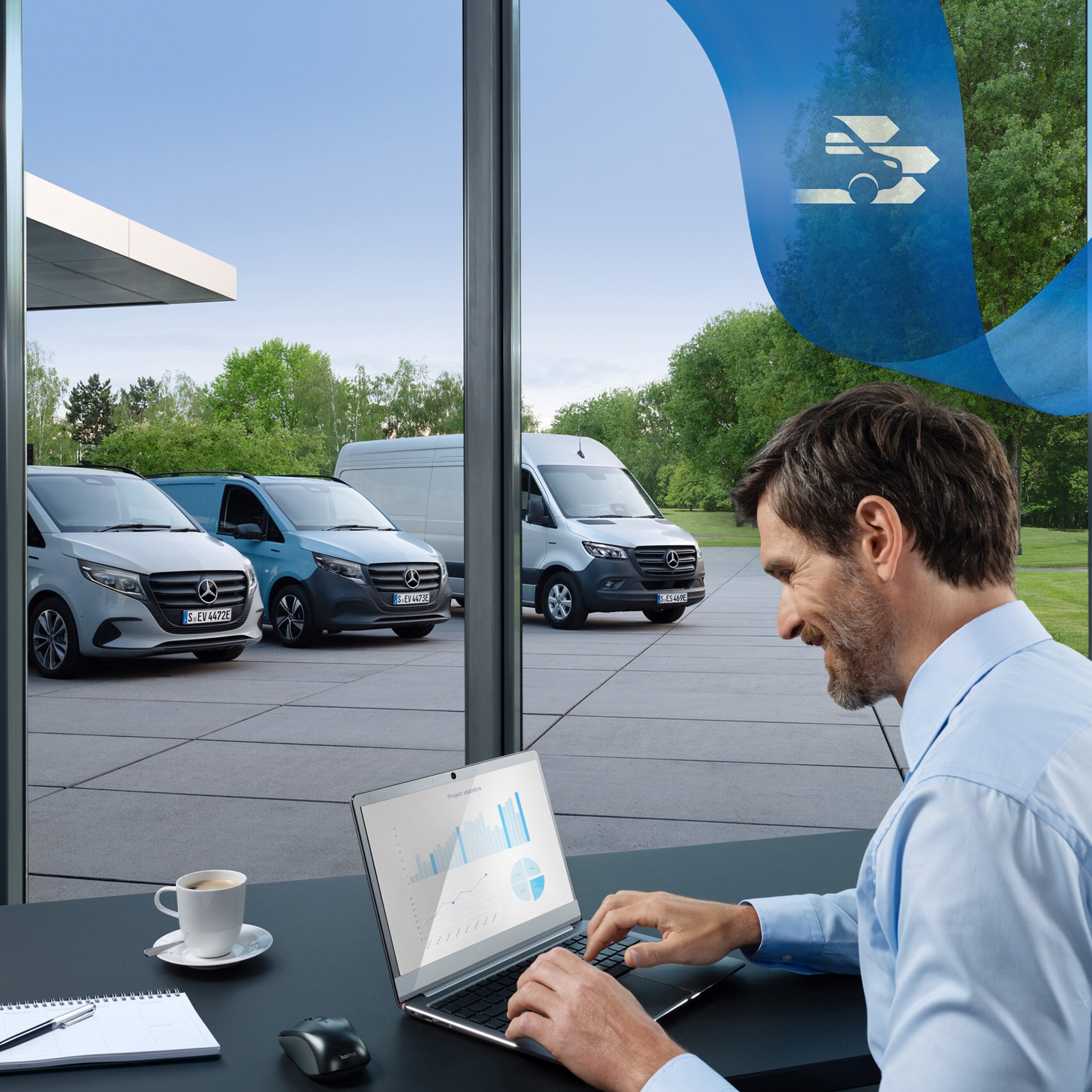 Een man gebruikt een laptop in een kantoor met op de achtergrond een reeks Mercedes-Benz Bedrijfswagens.