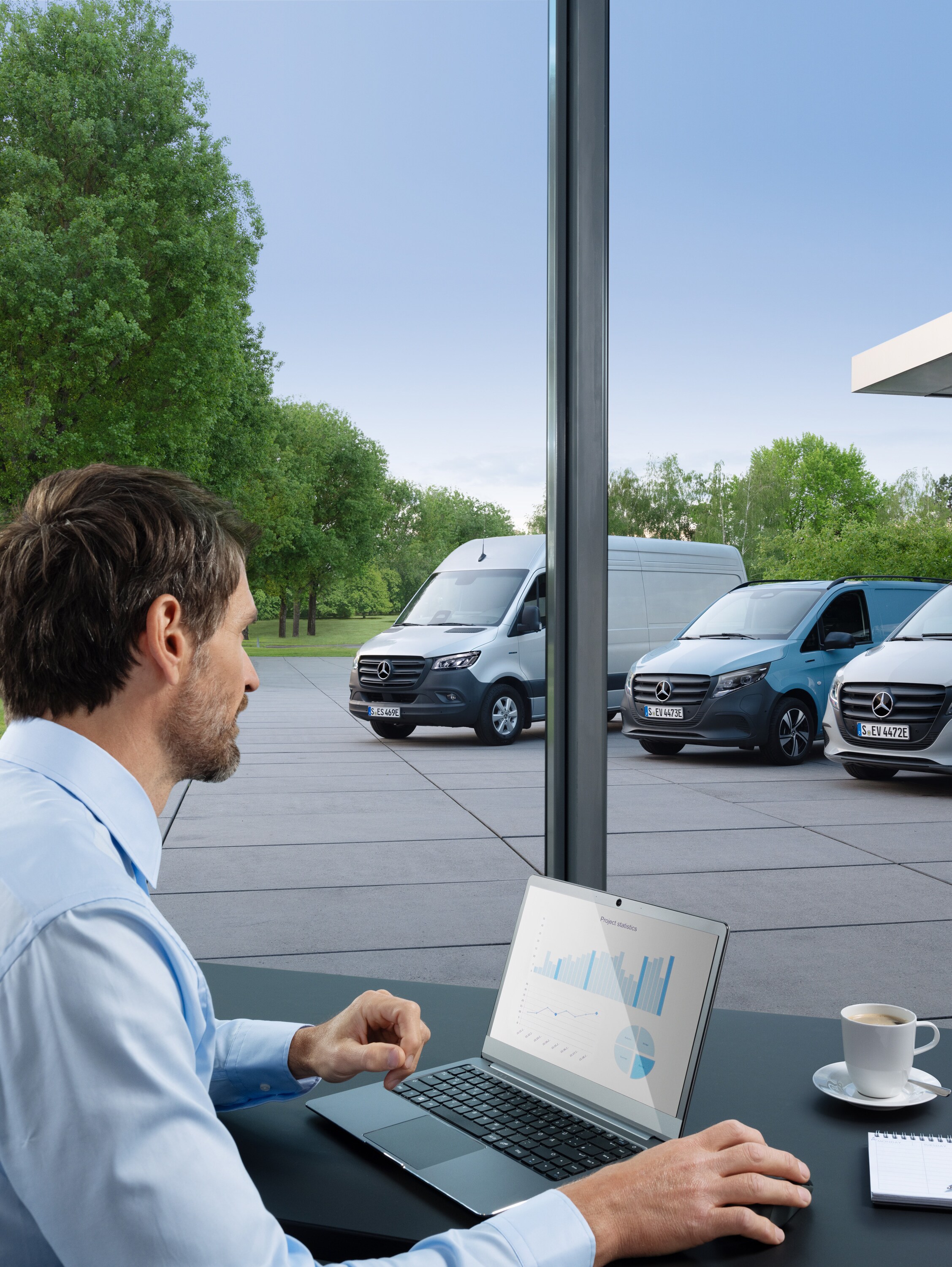 Man die met een laptop meerdere geparkeerde Mercedes-Benz bedrijfswagens bewaakt, symbool voor digitaal wagenparkbeheer.
