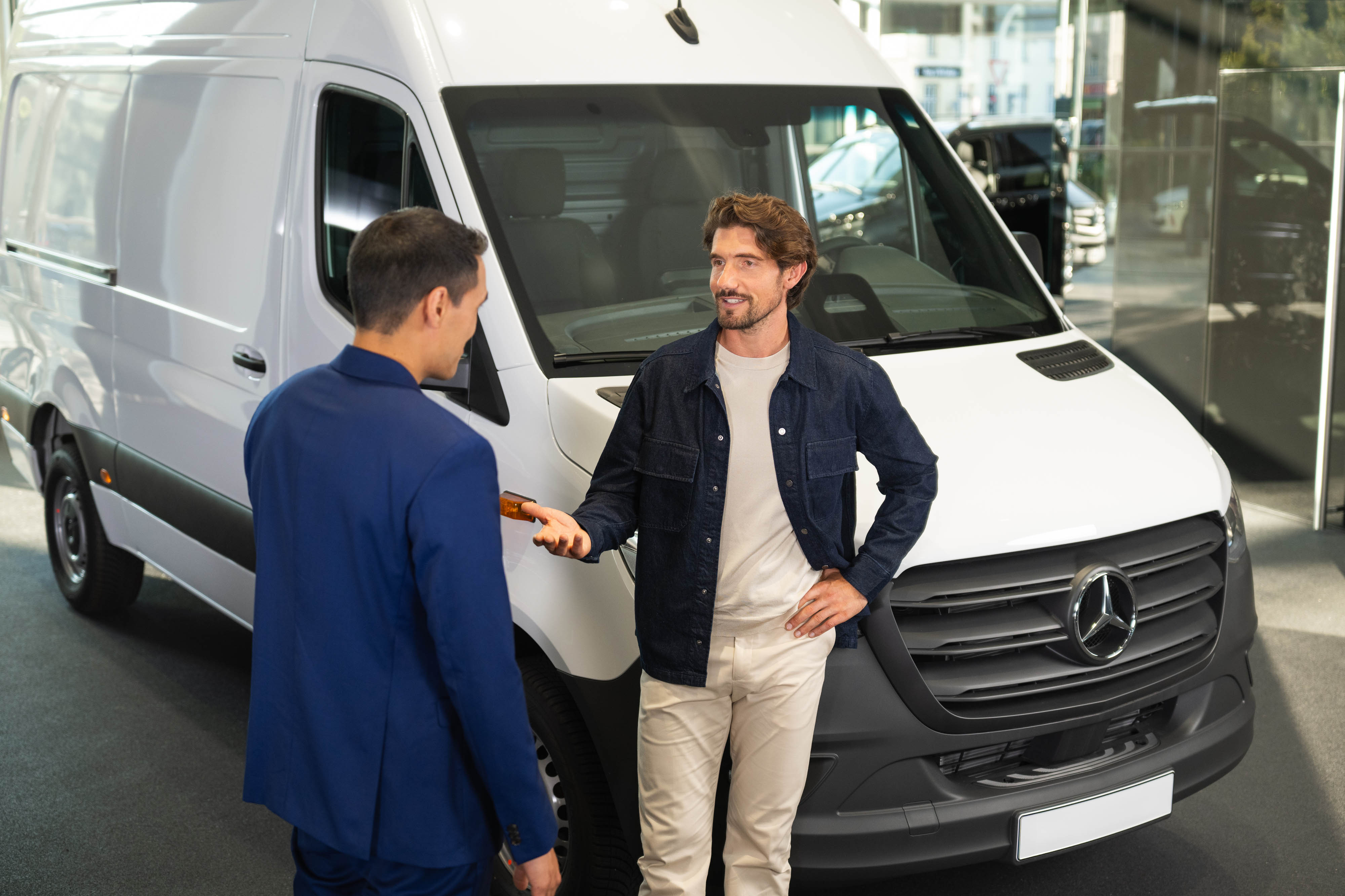 Mannen bespreken een Mercedes-Benz bestelwagen Twee mannen bij een witte Mercedes-Benz bestelwagen.