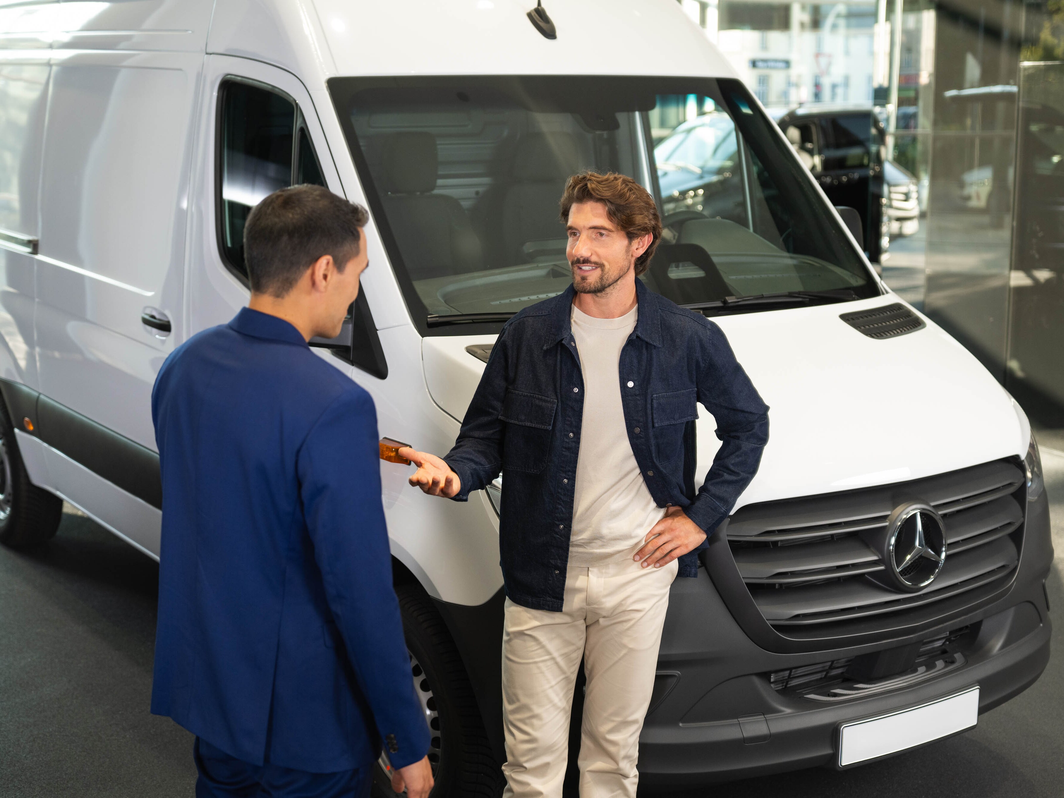 Deux hommes près d’un fourgon Mercedes-Benz blanc.