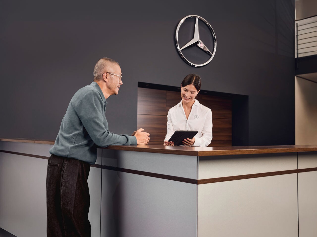 Klant wordt geholpen door een medewerker aan de receptiebalie van een Mercedes-Benz vestiging.