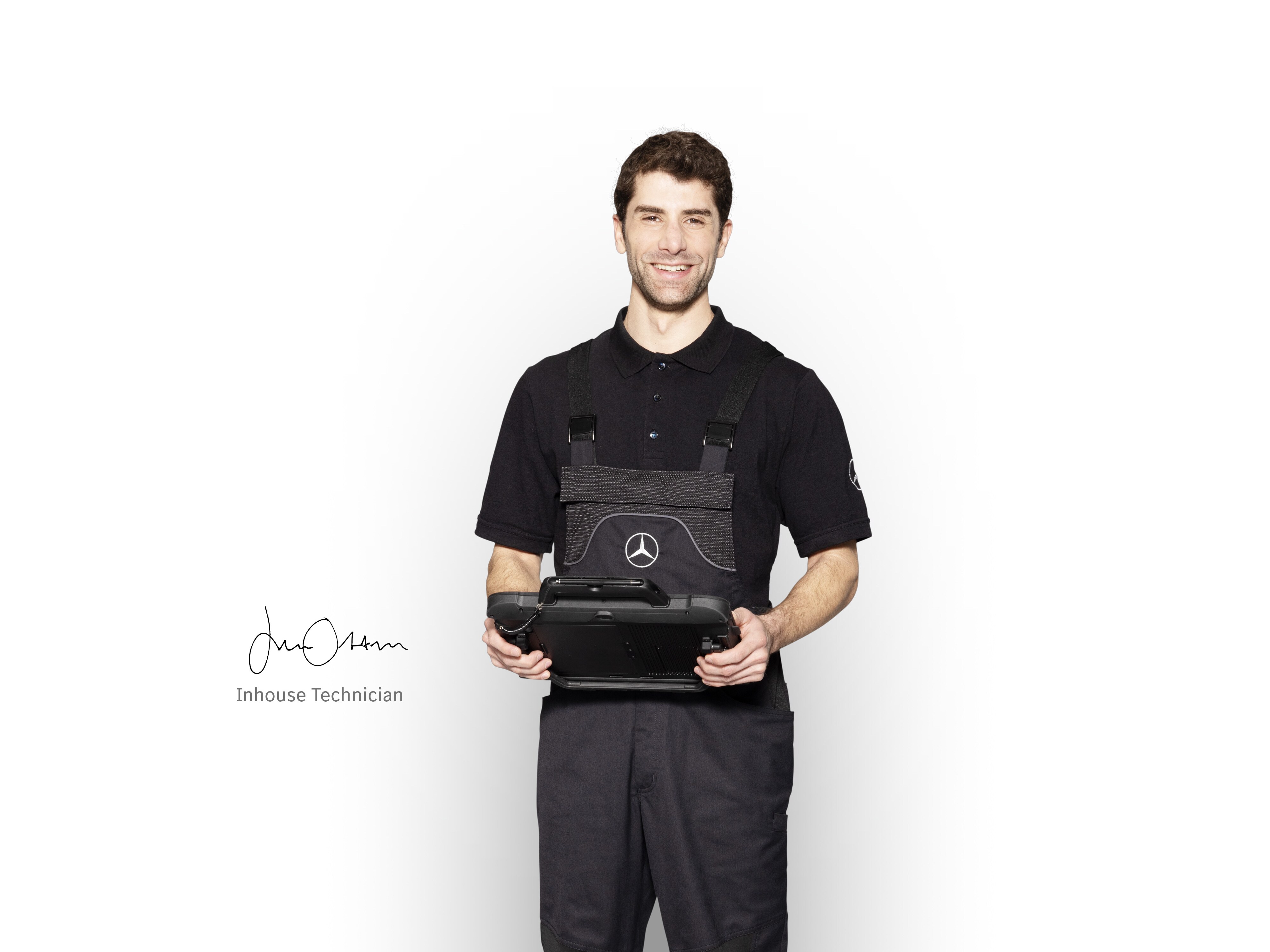 Mécanicien Mercedes-Benz en tenue de travail, tenant une tablette prête pour le signalement des dommages.